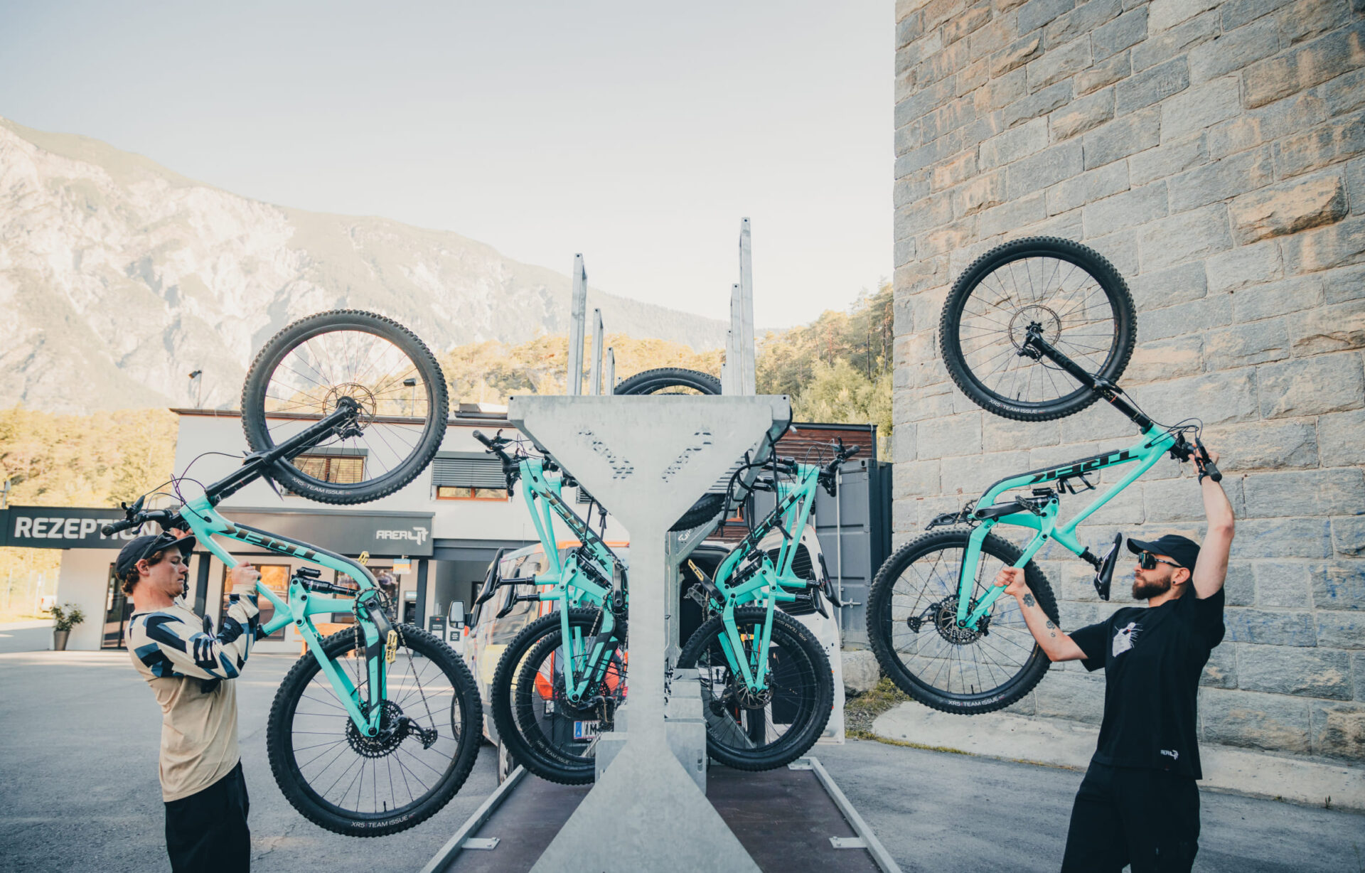 Zwei Männer heben ihre Mountainbikes vor einem Fahrradständer in der AREA 47 im Ötztal, Tirol