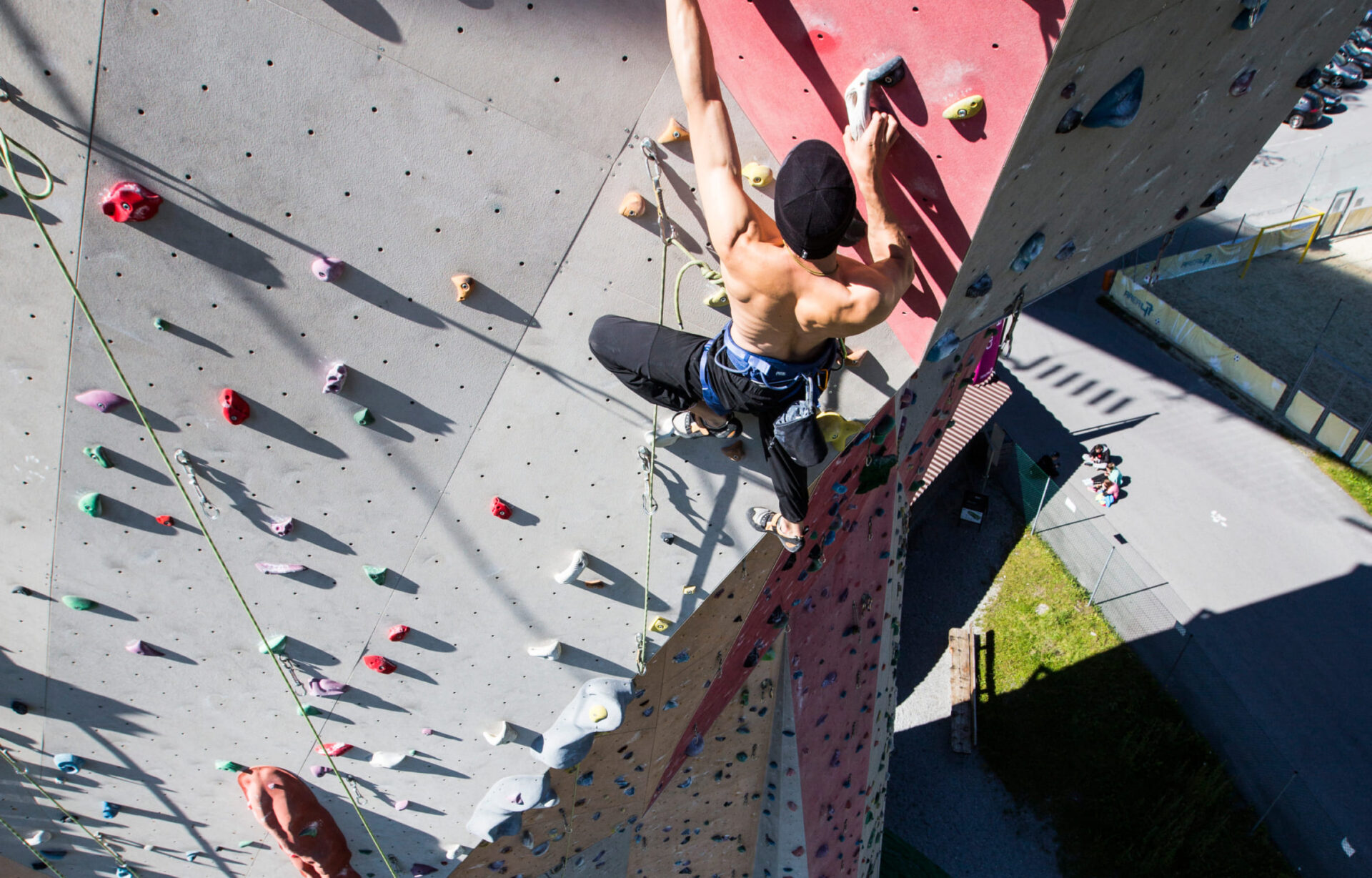 A climber on the outer wall of the climbing tower at AREA 47 in Ötztal, Tyrol, with a mountain panorama in the background