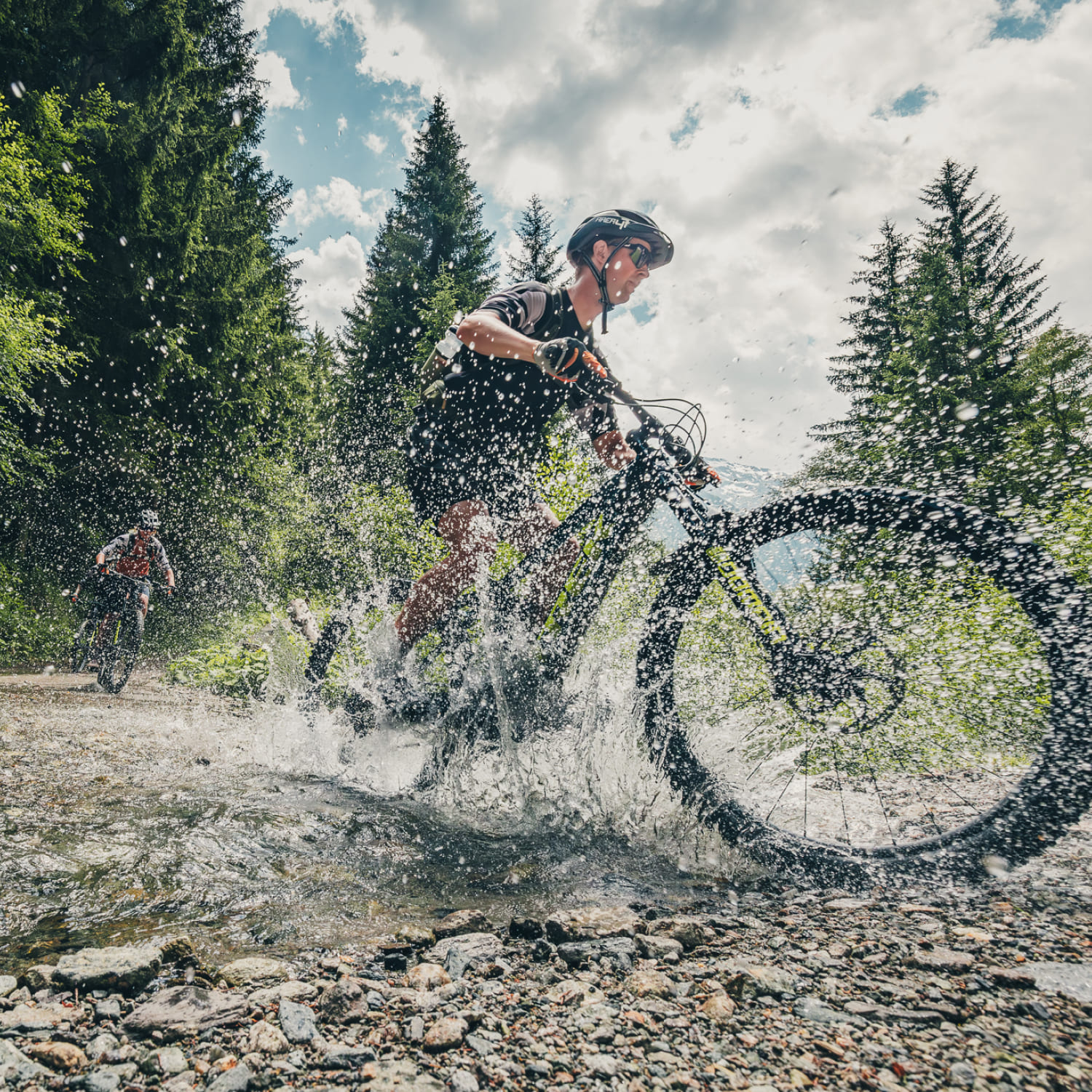 Mountainbiker fahren durch einen Bach in der AREA 47 im Ötztal, Tirol