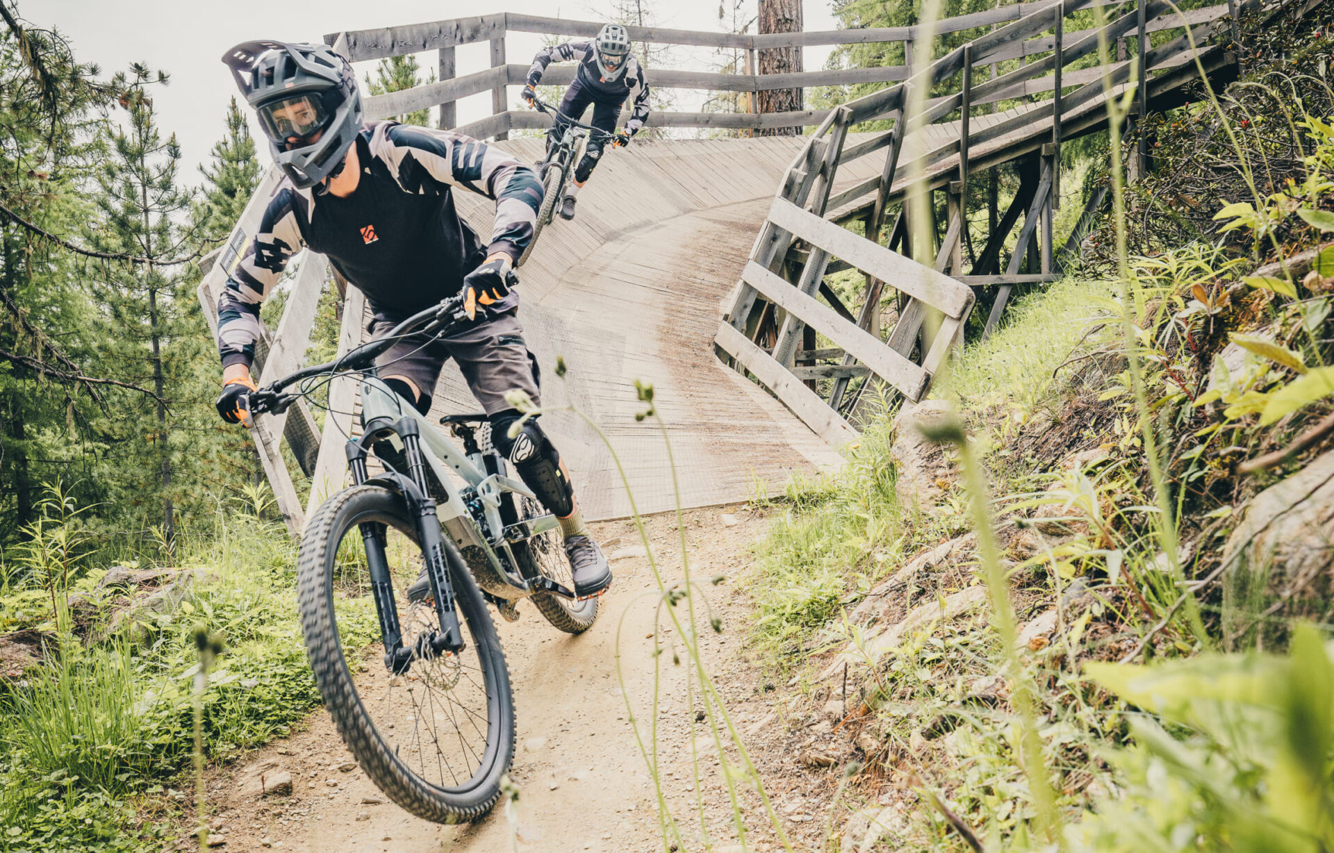 Mountain biker crosses a wooden footbridge in the AREA 47 bike park in Ötztal, Tyrol