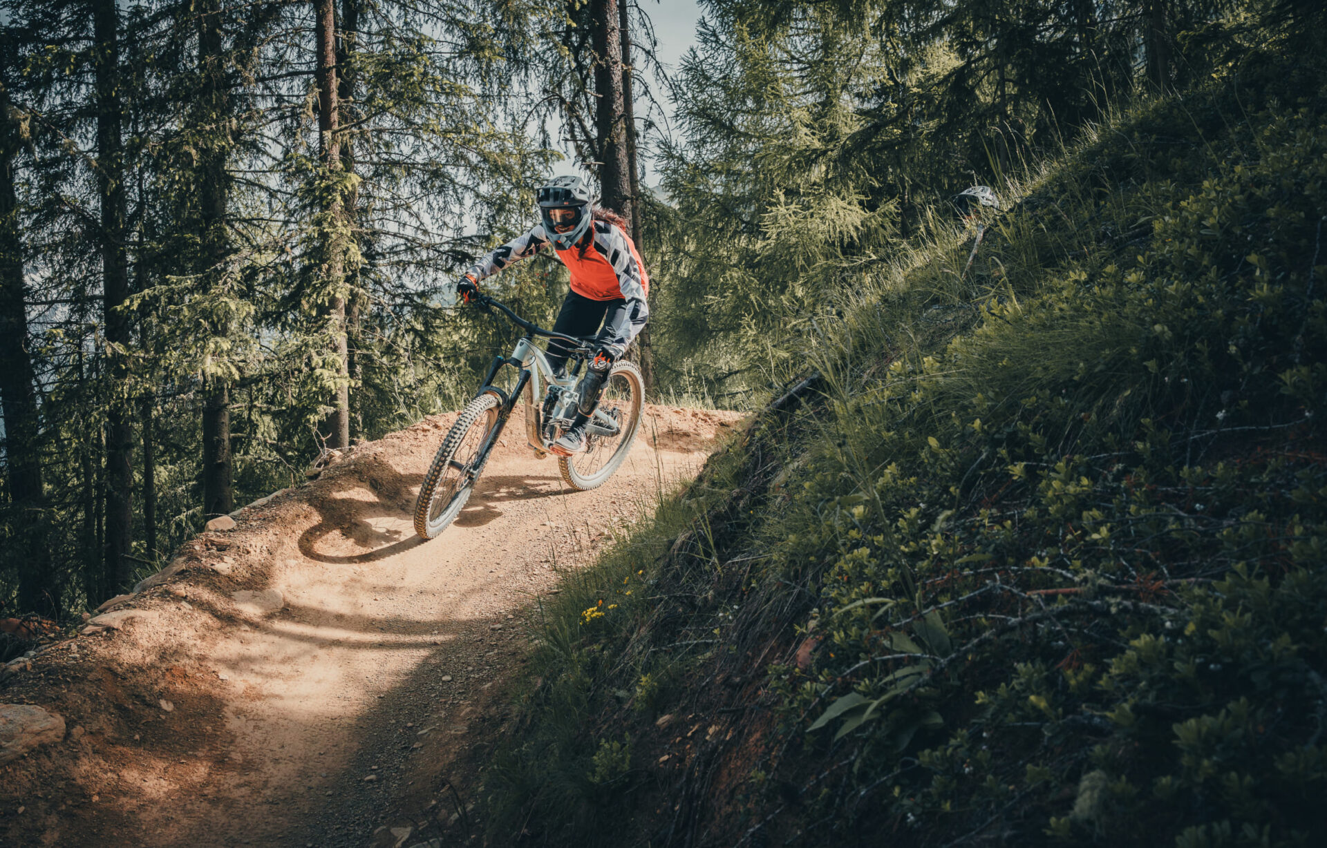 Mountain biker riding through a forest trail in the AREA 47 in Ötztal, Tyrol