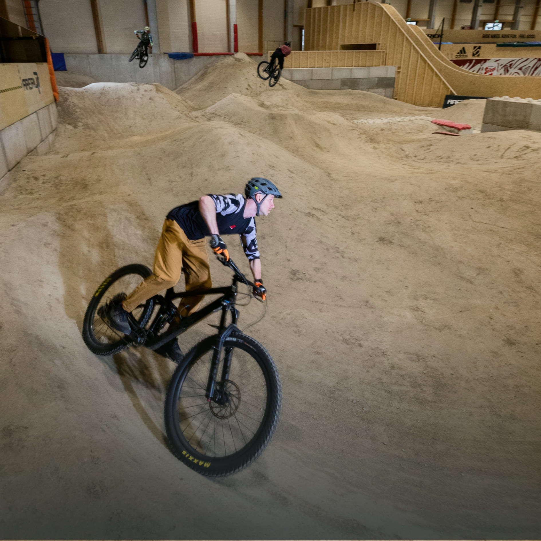 Mountainbiker in der Indoor-Bikepark-Anlage der AREA 47 im Ötztal, Tirol, während einer rasanten Fahrt durch die sandige Strecke