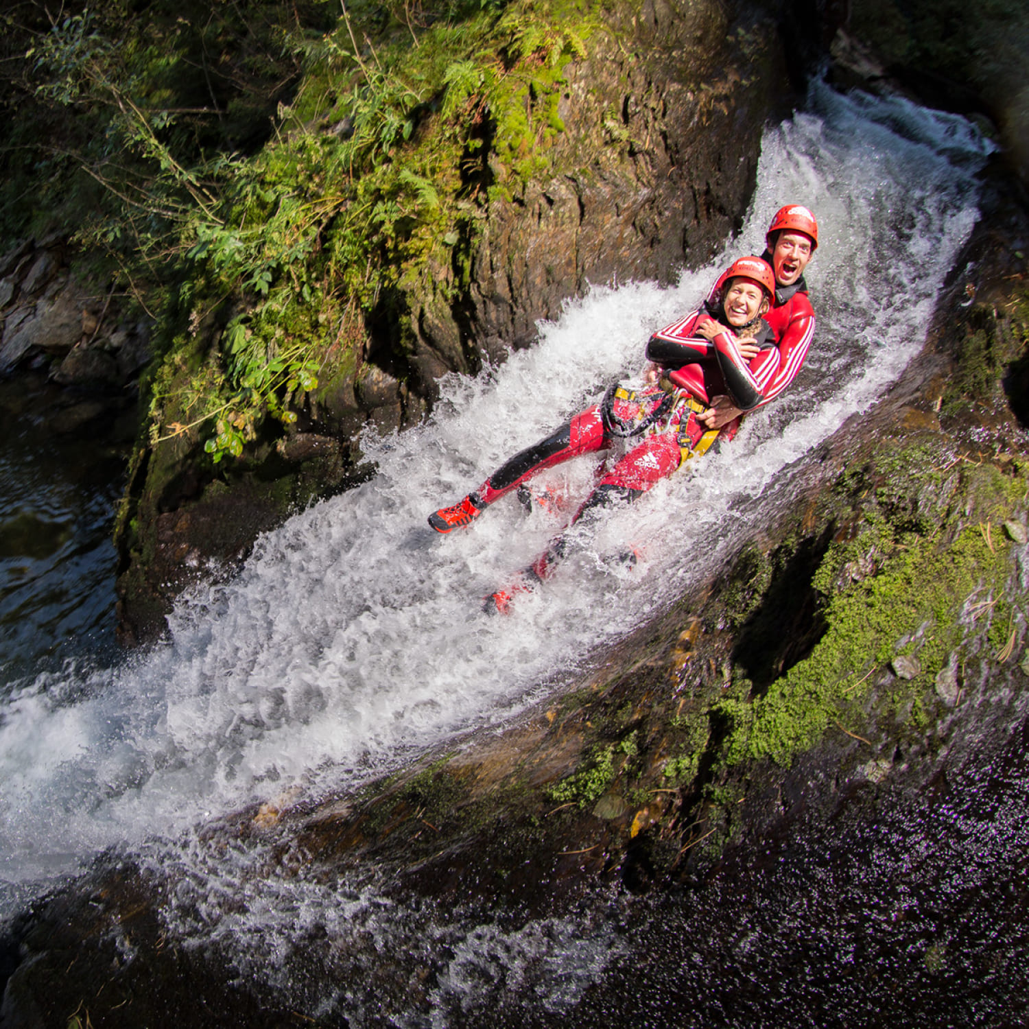 Canyoning-Teilnehmer gleiten gemeinsam durch eine enge Wasserpassage in der AREA 47 im Ötztal, Tirol