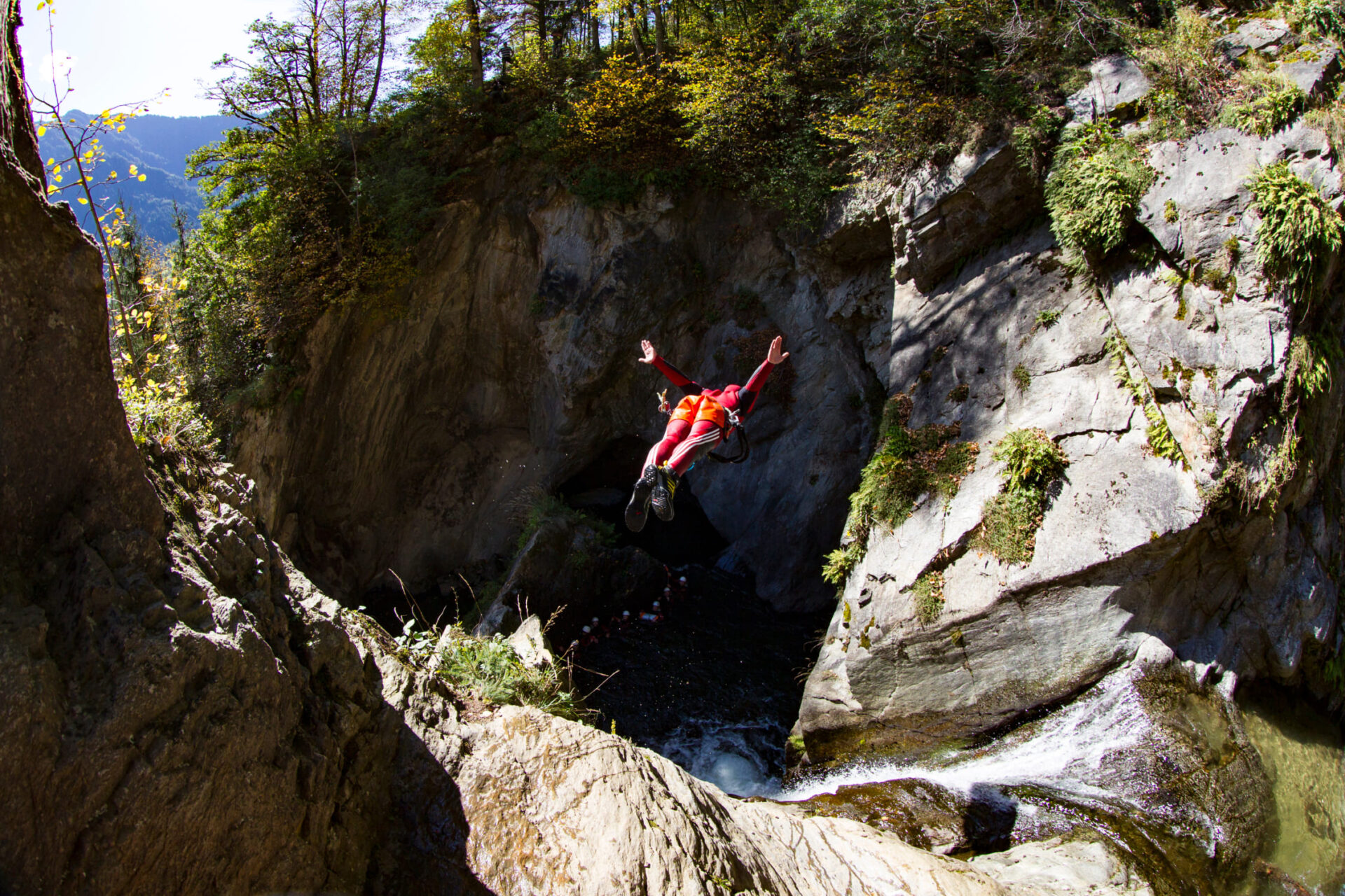 Teilnehmer springt von einer Klippe beim Canyoning in der AREA 47, Tirol
