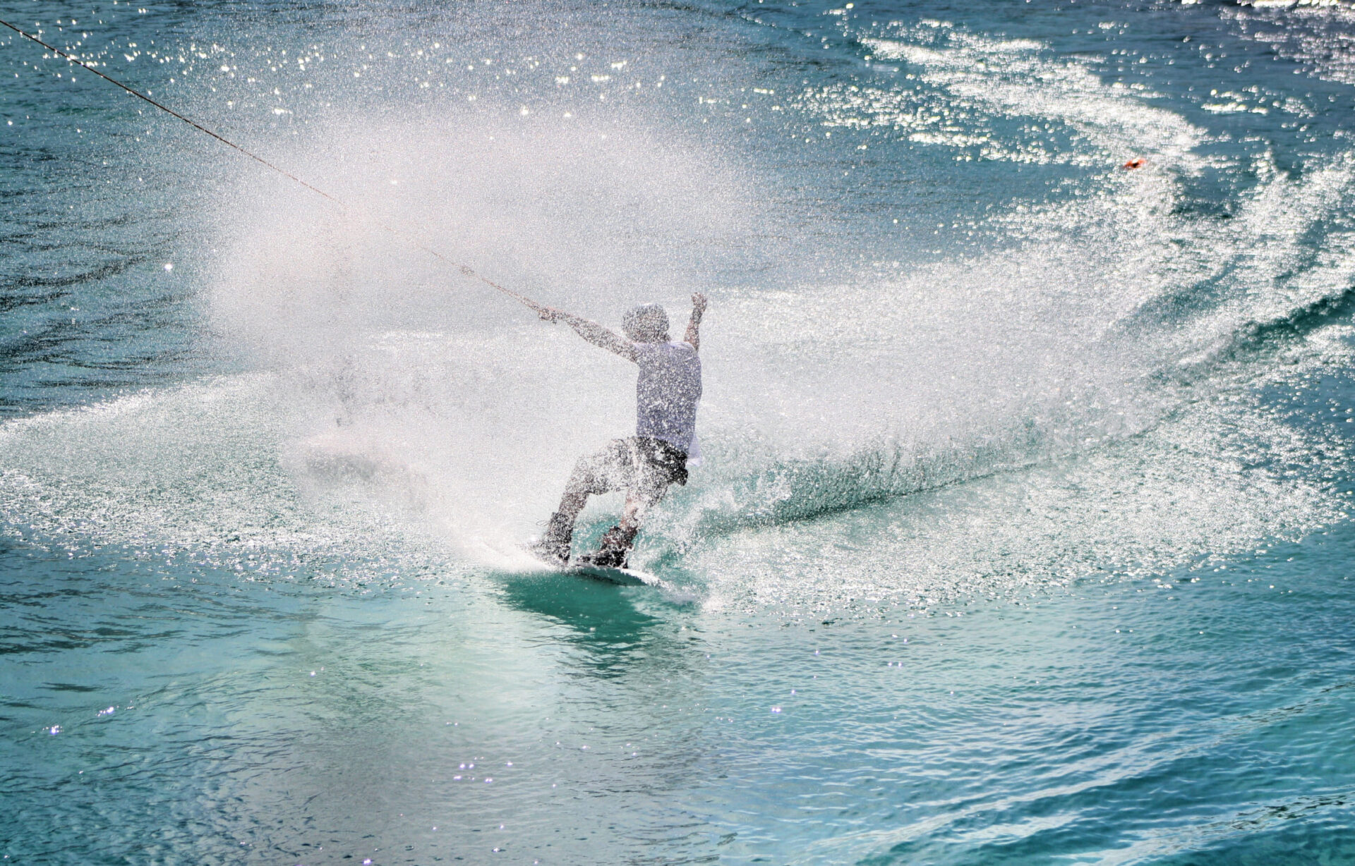 Person beim Wakeboarden in der Wake AREA der AREA 47 im Ötztal, Tirol, mit großem Wasserspritzer