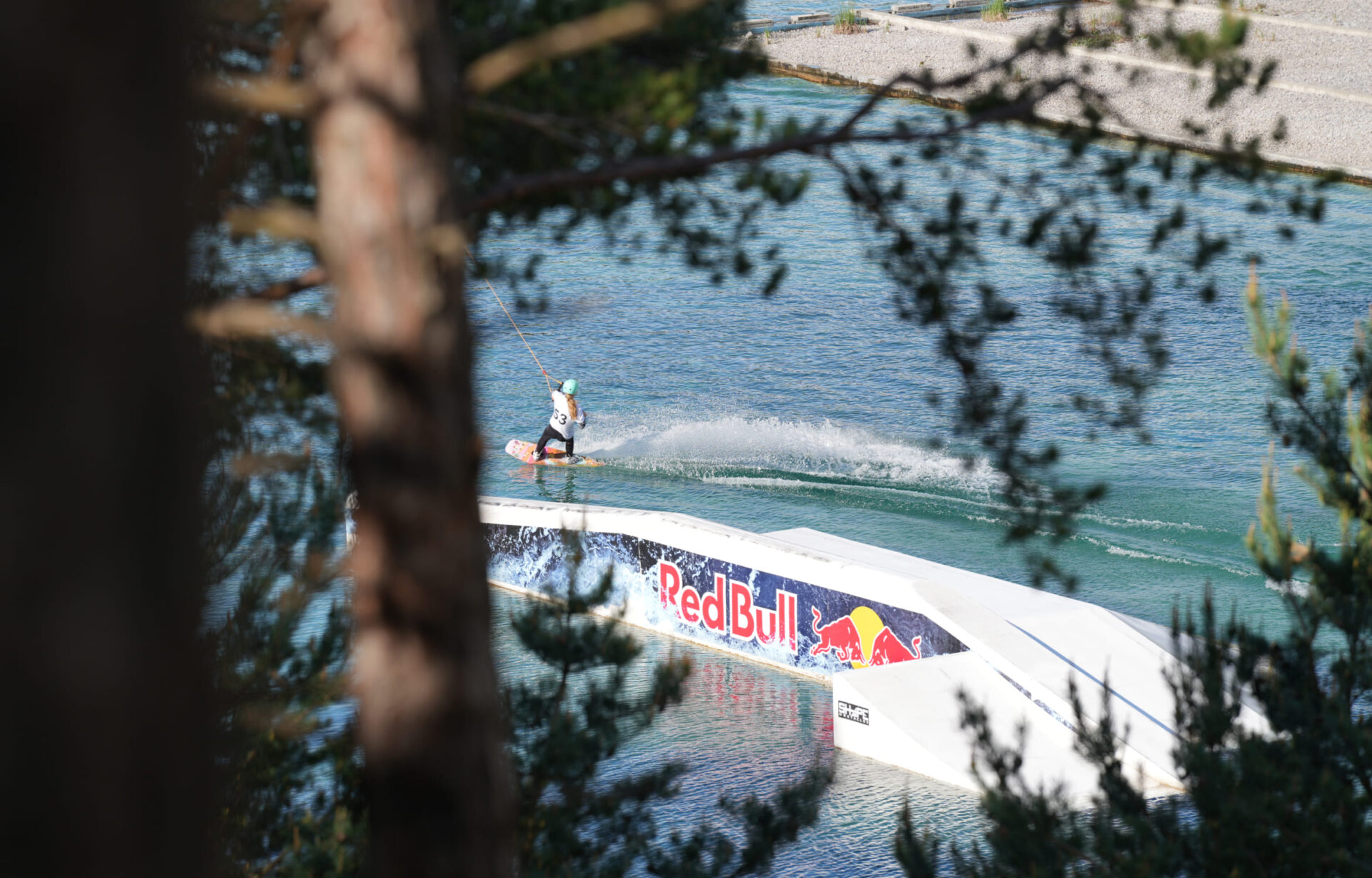 Wakeboarder hinter Bäumen in der Wake AREA der AREA 47 im Ötztal, Tirol