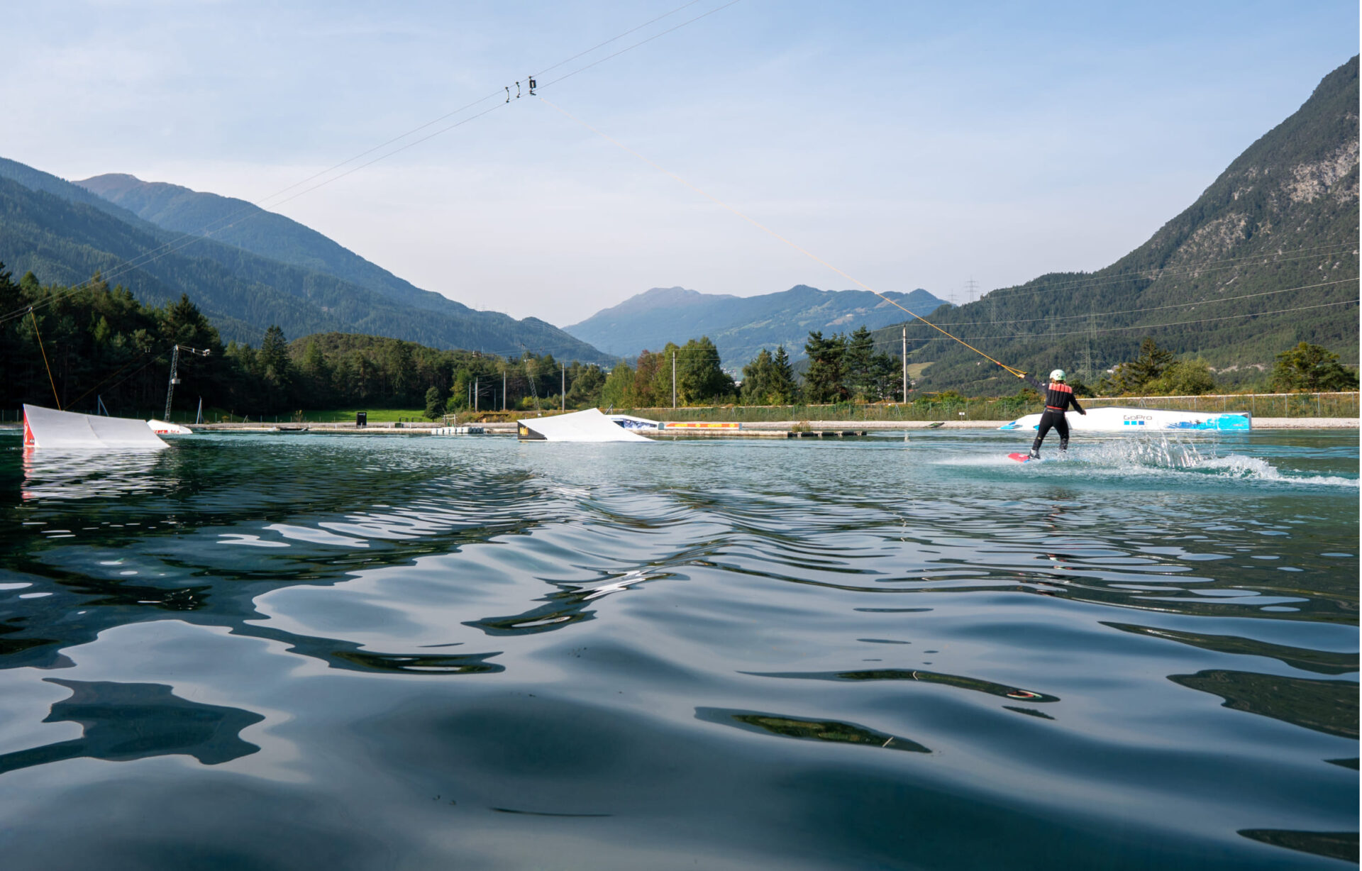 Wakeboarder fährt über die Wake AREA mit Bergkulisse in der AREA 47 im Ötztal, Tirol