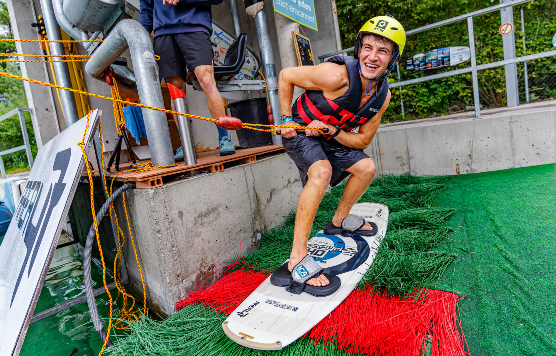 Teilnehmer posiert mit Helm und Wakeboard in der Wake AREA der AREA 47 im Ötztal, Tirol