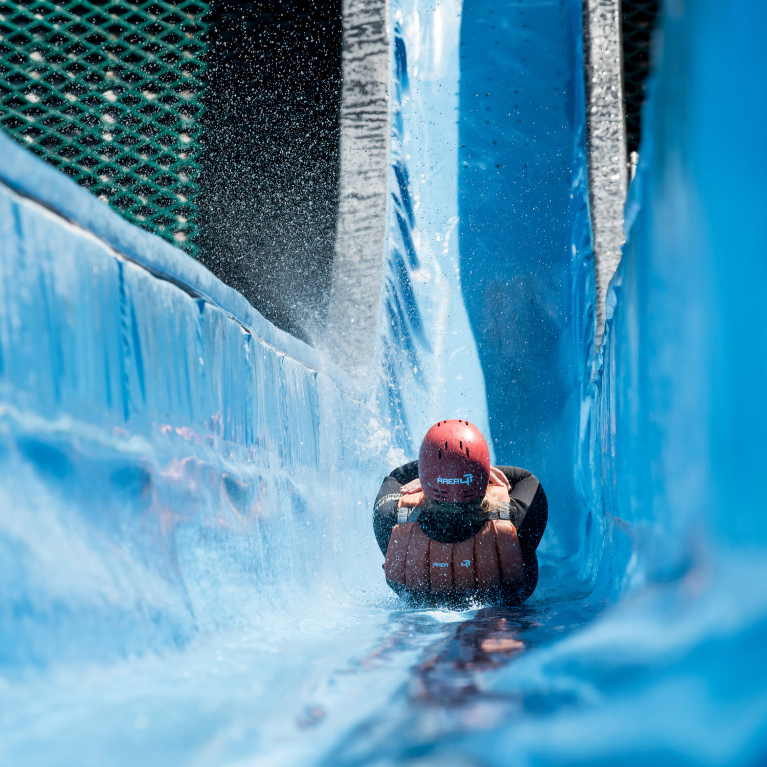 Person with helmet and life jacket on the Slip'n'Slide slide at AREA 47 in Ötztal, Tyrol