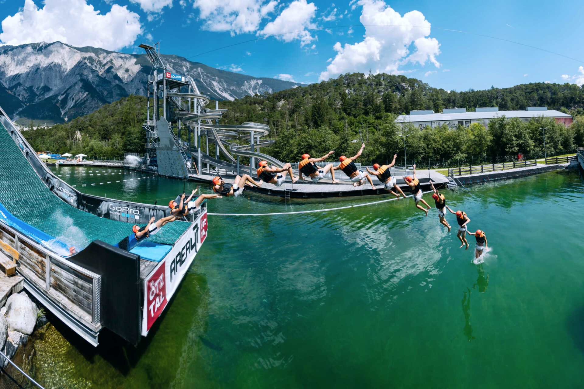 Person with life jacket on a slip'n'slide ramp at AREA 47 in Ötztal, Tyrol, jumping into the water