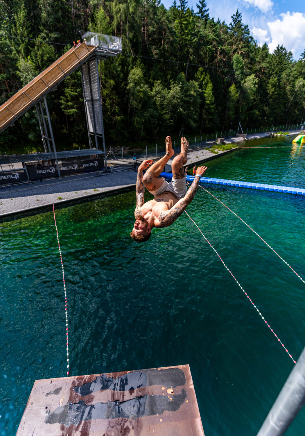 Man jumps with a backflip from a platform into the Water AREA of AREA 47 in Ötztal, Tyrol