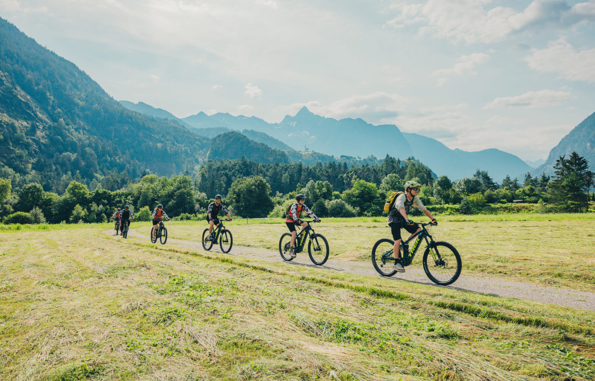 Gruppe von Radfahrern auf einer E-Mountainbike-Tour durch eine grüne Landschaft im Ötztal, Tirol