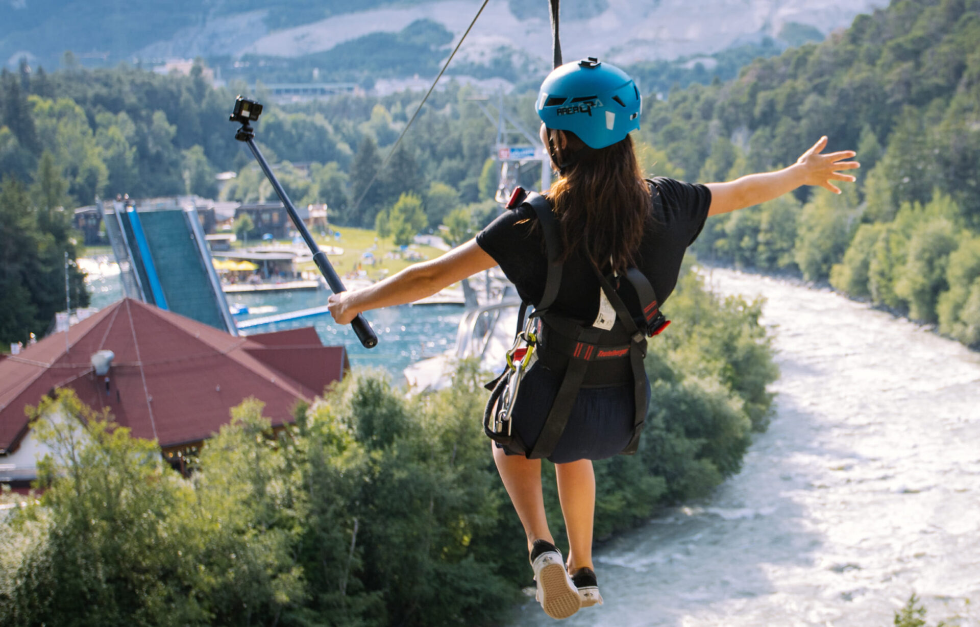 Person mit Sicherheitsgurt und Helm schwebt an einer Zipline über die Water AREA der AREA 47 im Ötztal, Tirol