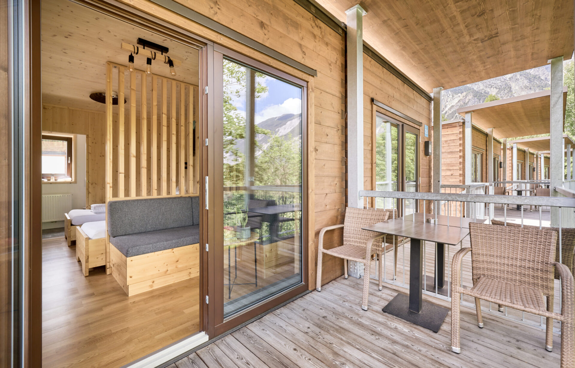Blick auf die Terrasse eines Doppelzimmer Plus in der AREA 47 im Ötztal, Tirol, mit Sitzmöbeln und Holzdetails