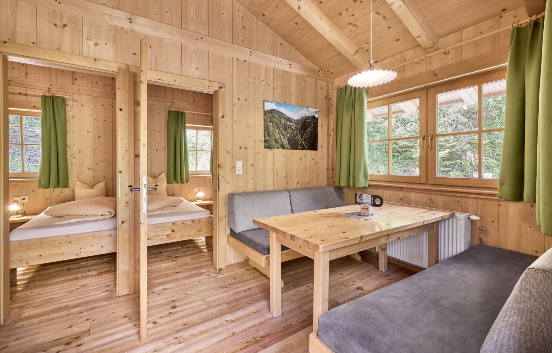 Innenansicht einer gemütlichen Holz-Lodge in der AREA 47 im Ötztal, Tirol, mit zwei Schlafzimmern, einer Sitzecke und großen Fenstern