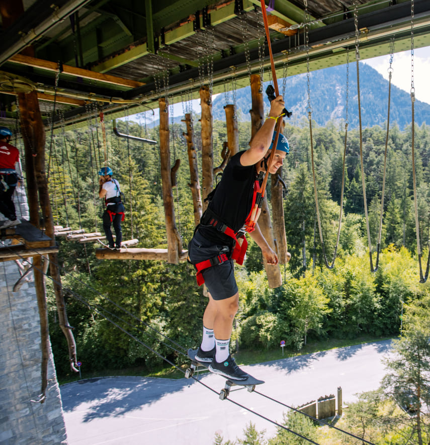 Teilnehmer im Hochseilgarten der AREA 47 im Ötztal, Tirol, balanciert über eine Seilbrücke in luftiger Höhe
