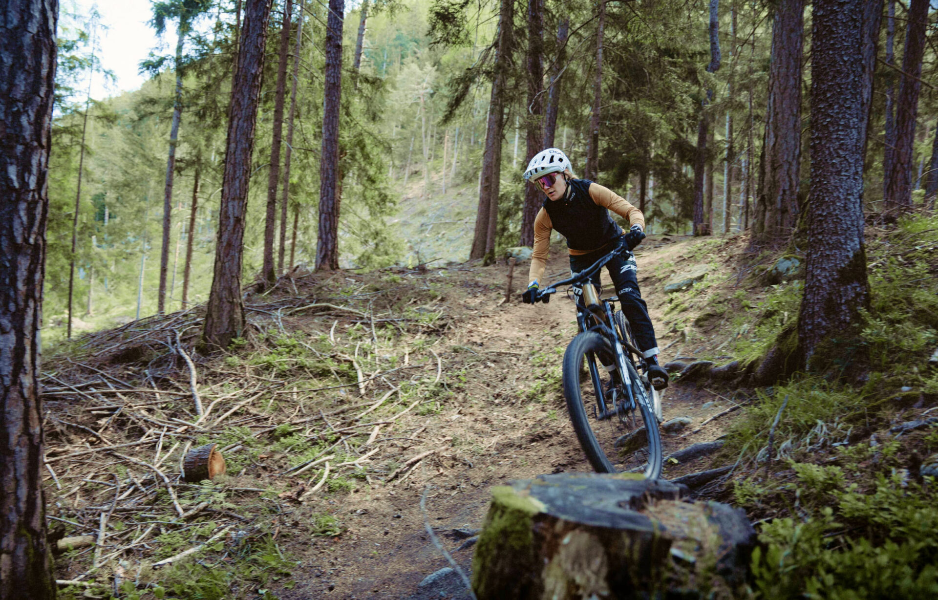 A mountain biker riding on a narrow trail through the forest