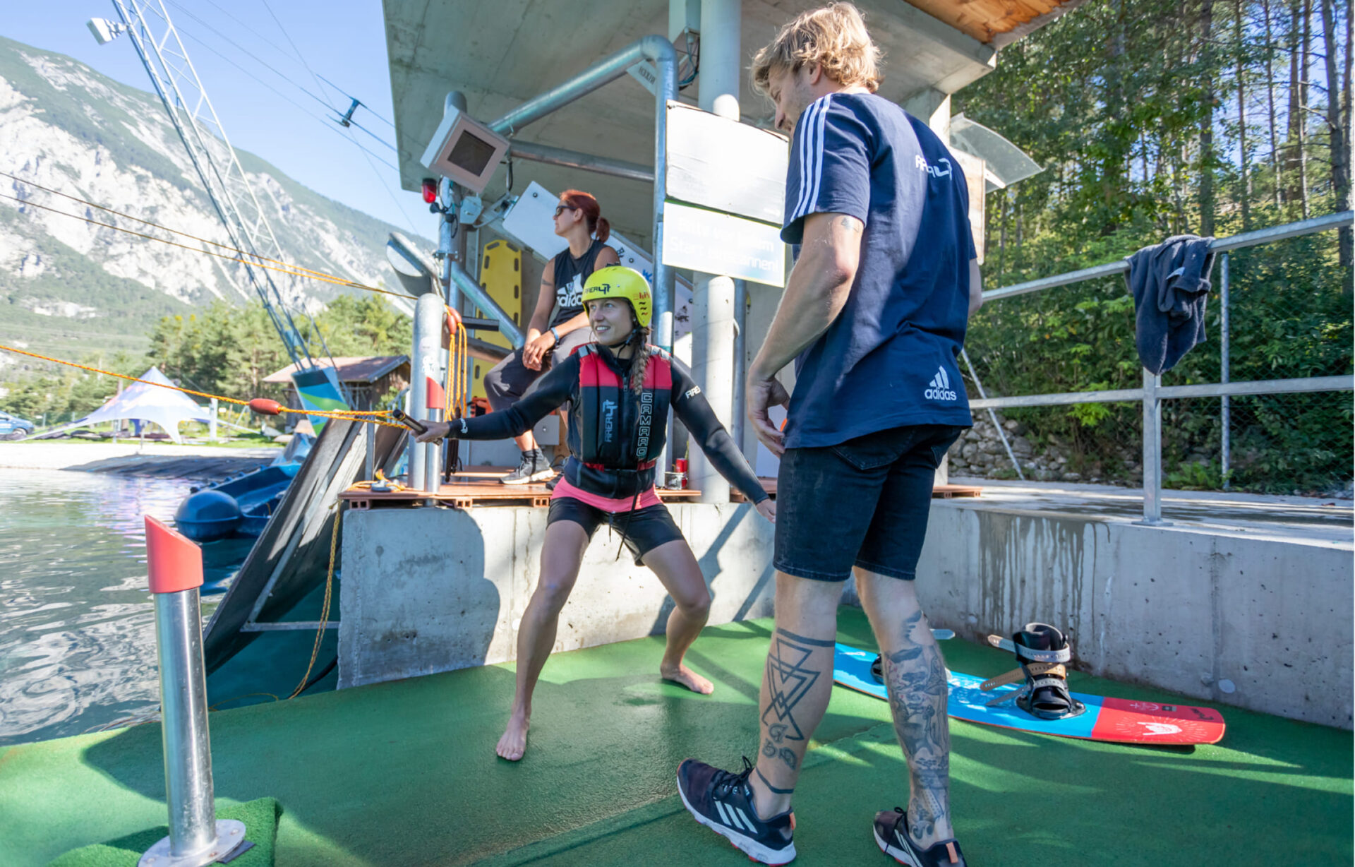 Wakeboard coach assisting a beginner with the handle near the shore at AREA 47 in the Ötztal, Tyrol.