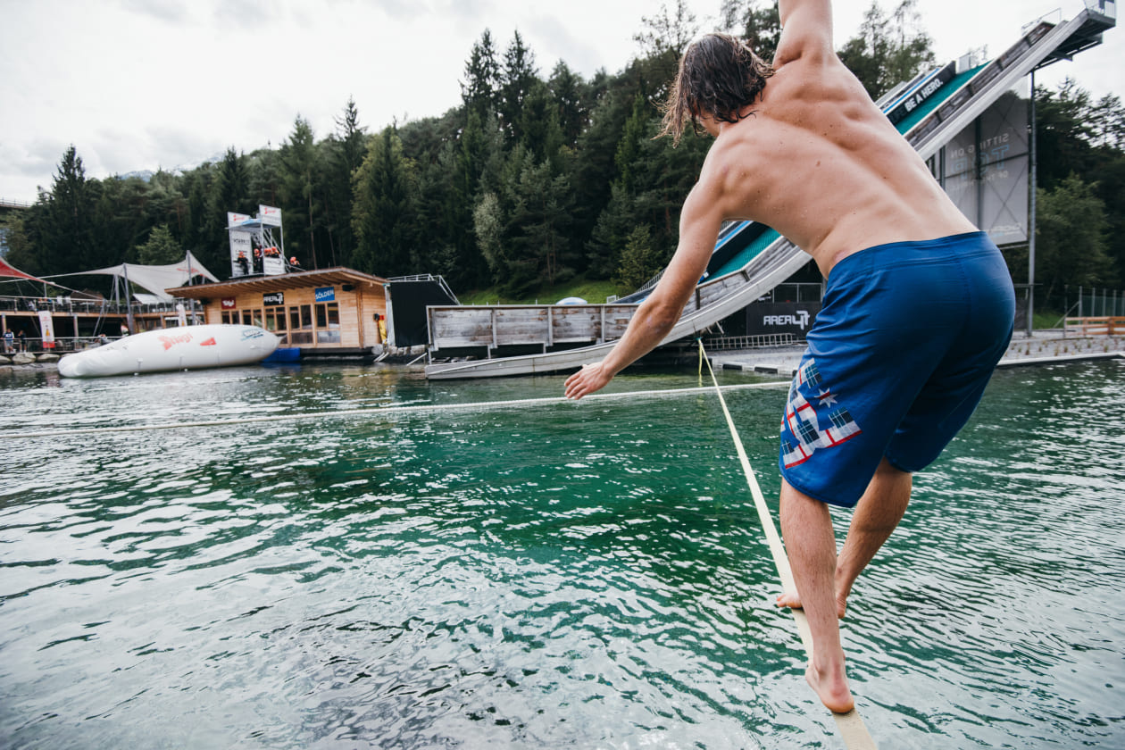 Mann balanciert auf einer Slackline über dem Wasser in der AREA 47 im Ötztal, Tirol
