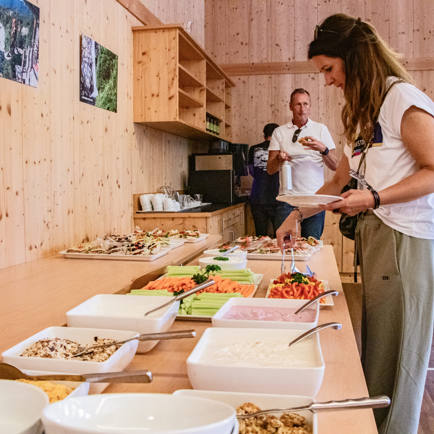 A woman serving herself at a buffet with fresh vegetables, dips, and snacks at AREA 47, Ötztal, Tirol