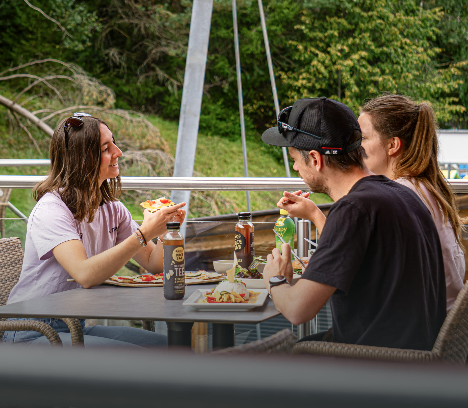 Three people eat together on the terrace of the Lakeside Restaurant in AREA 47, Ötztal, Tyrol