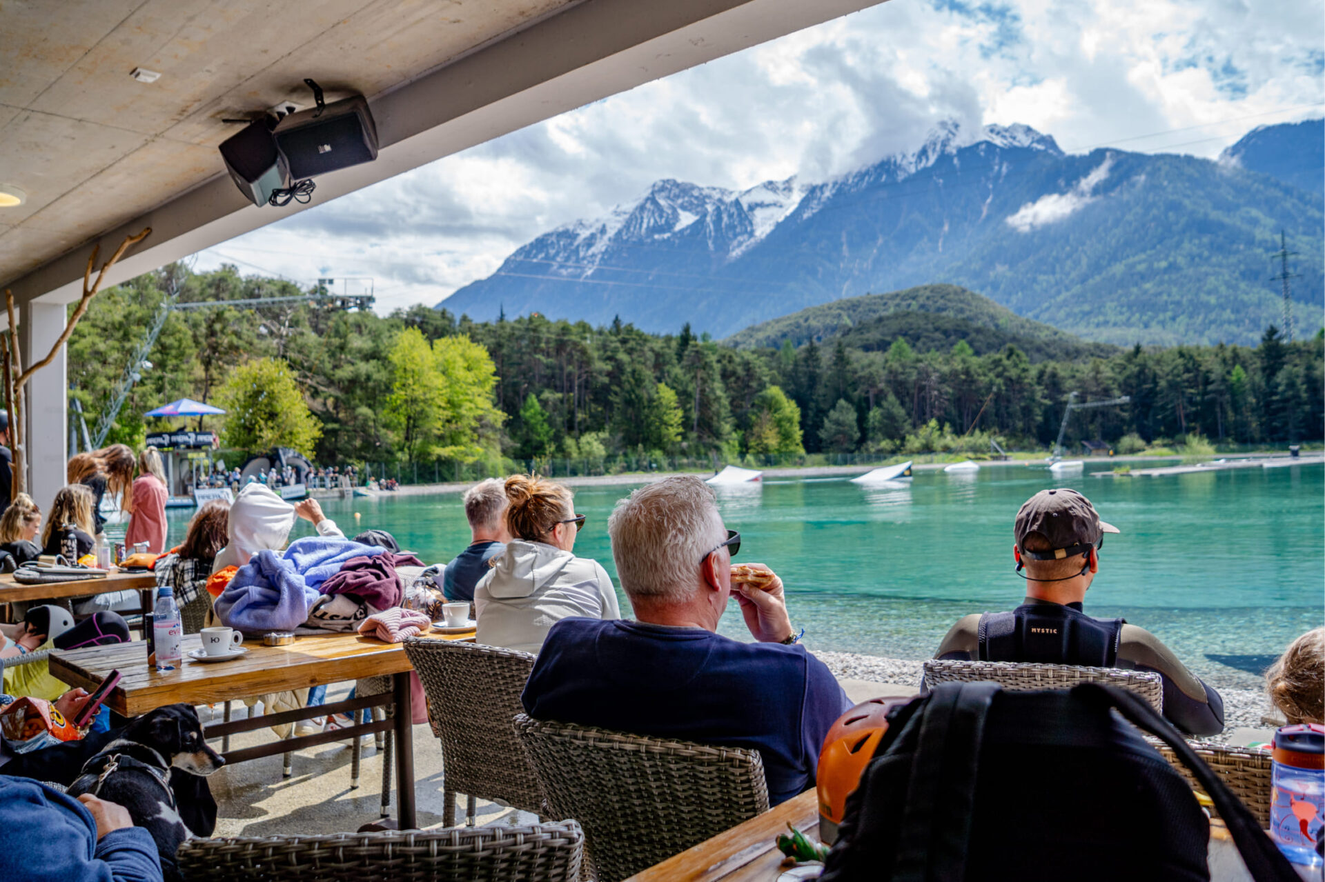 Guests in the Wake Café at AREA 47 with a view of the Water AREA in Ötztal, Tyrol