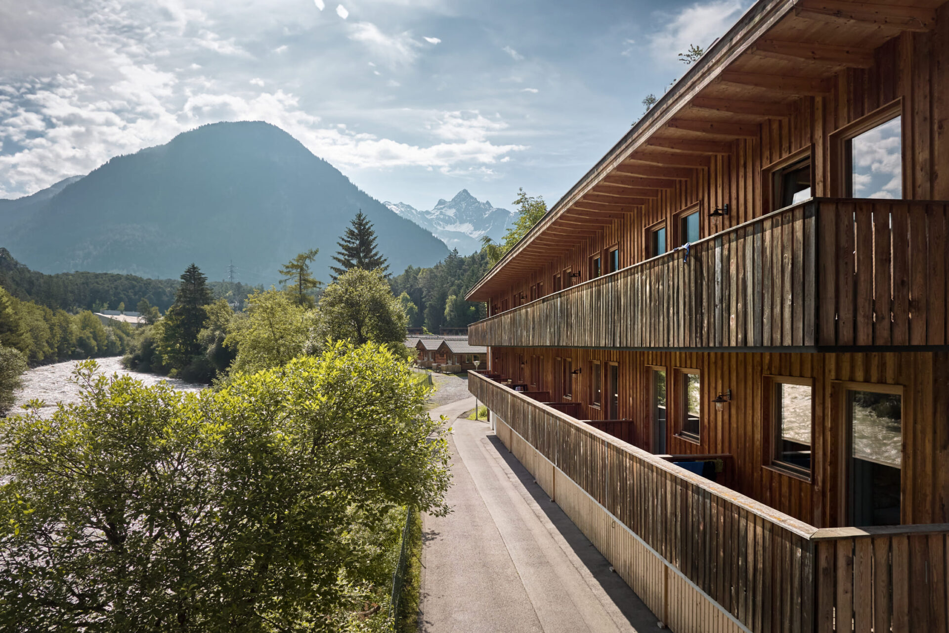 Holzgebäude in der AREA 47, Ötztal, Tirol, umgeben von Fluss und Bergen